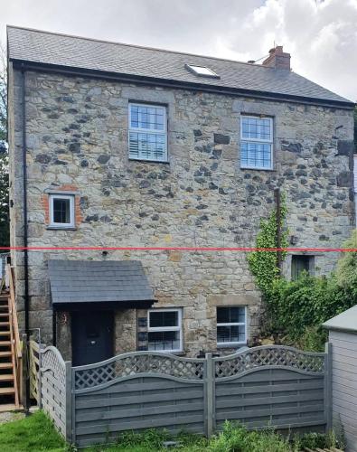 an old stone house with a fence in front of it at The Annexe At The Old Mill in Camborne