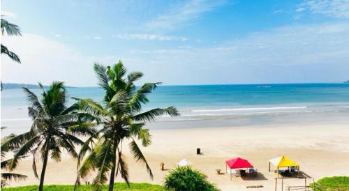 a beach with tents and palm trees and the ocean at Southbeach Weligama in Weligama