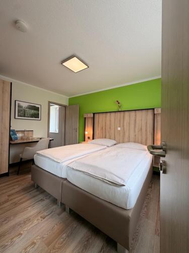 a bedroom with a large bed with a green wall at Schlüter Hotel & Restaurant in Wankendorf