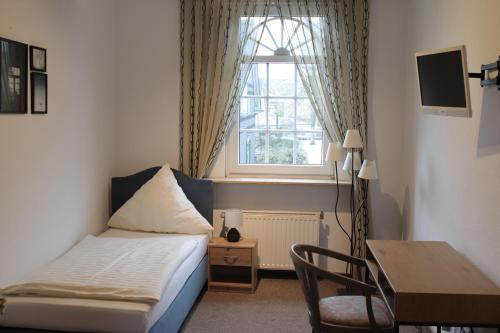 a small bedroom with a bed and a window at Hotel Alt-Lennep in Remscheid