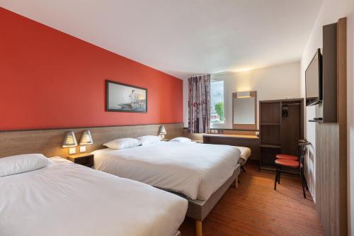 two beds in a hotel room with red walls at Ace Hotel Chateauroux Déols in Déols