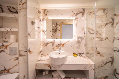 ein weißes Badezimmer mit Waschbecken und Spiegel in der Unterkunft Creta Mare Hotel in Plakias