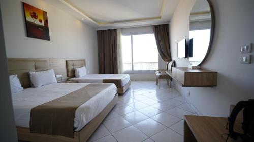 a hotel room with two beds and a mirror at King Tut Aqua Park Beach Resort in Hurghada