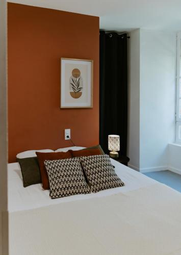 a bedroom with a large white bed with a brown wall at Villa de Meslay in Montaigu-Vendée