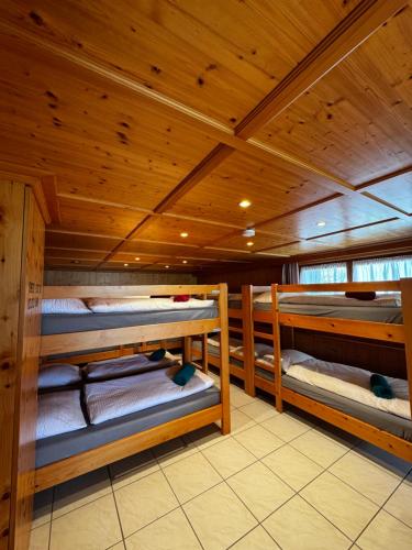 a room with three bunk beds in a wooden cabin at Haus Bünten in Quinten