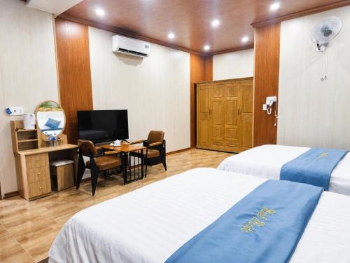 a hotel room with two beds and a desk and a television at Panda Hotel in Long Thành