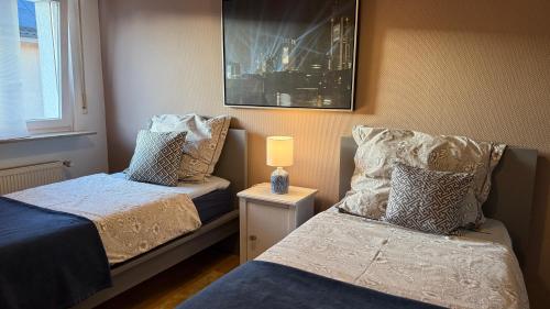 a bedroom with two beds and a lamp on a table at Double M Apartment in Seligenstadt