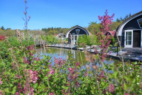 a garden with a pond and buildings and flowers at 't Landgoed Baars in Baars