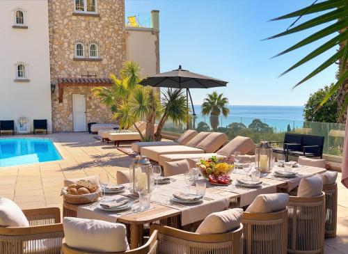 a patio with a table and chairs and a pool at Sea View Villa Roc d'Azur - Pool - Jacuzzi in Vallauris