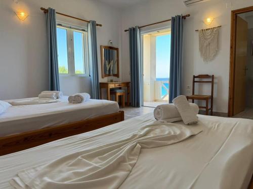 two beds in a bedroom with a view of the ocean at Kofini Falassarna in Falasarna