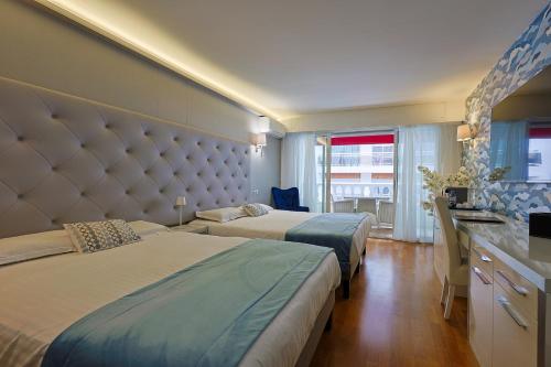 a hotel room with two beds and a large headboard at Hotel Le Fouquet's in Cannes