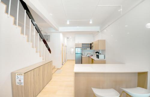 a kitchen with white walls and a counter and chairs at The Ostel Hostel Bangkok in Bangkok