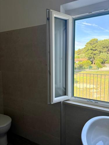 a bathroom with a window and a toilet and a sink at Elba Essence Suites in Portoferraio