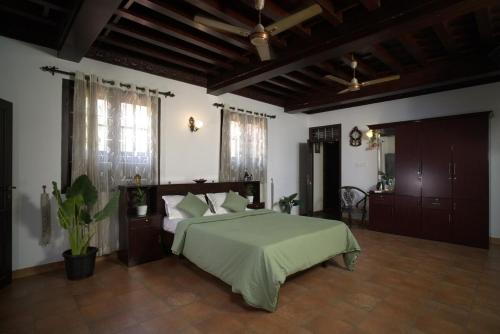 a bedroom with a large bed with a green blanket at Poomuttathillam in Kunnamangalam
