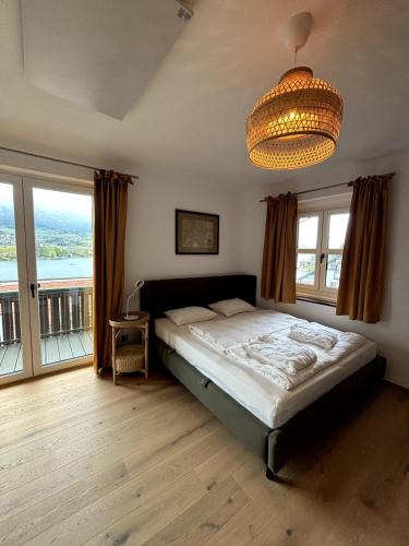 a bedroom with a bed and a chandelier at Chic & Cozy Lake View Apartment in Seeboden