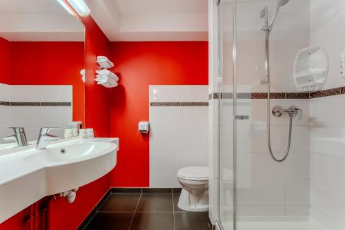 a bathroom with red walls and a toilet and a sink at Ace Hotel Montluçon in Saint-Victor