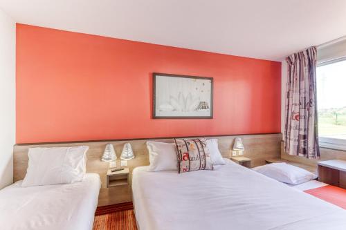 two beds in a room with a red wall at Ace Hotel Montluçon in Saint-Victor