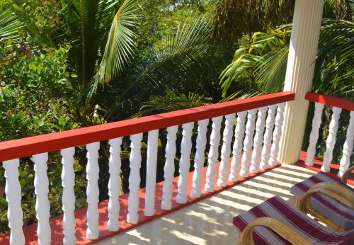 a porch with two chairs and palm trees at Namaste Yoga Farm in Gokarna