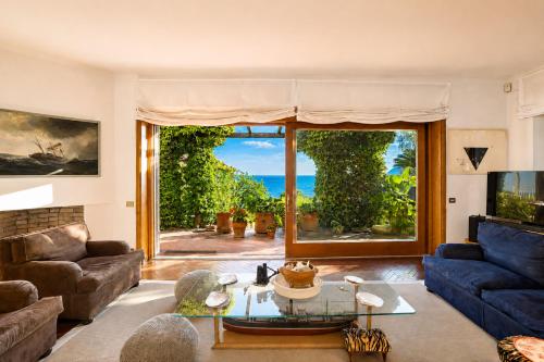 a living room with a blue couch and a large window at Hostdomus - Villa Gabriella with private pool in Alassio