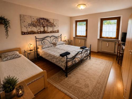 a bedroom with two beds and two windows at Casa Zarabara in Arta Terme