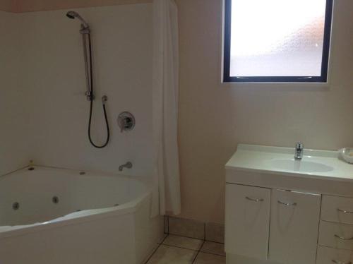 a bathroom with a bath tub and a sink at Central Park Motor Inn in Taumarunui
