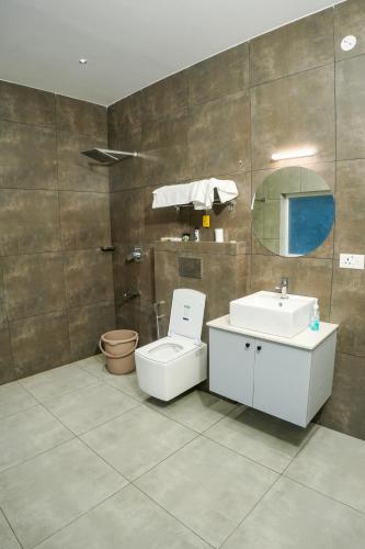 a bathroom with a toilet and a sink and a mirror at Gems Munnar in Anachal