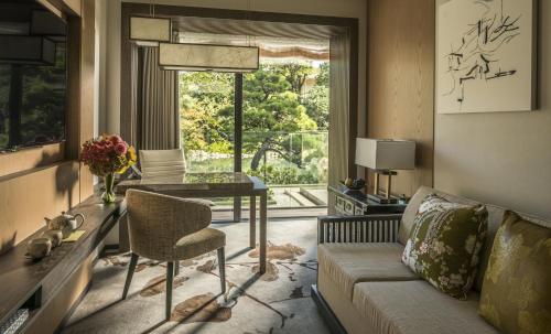a living room with a couch and a table and a window at Four Seasons Hotel Kyoto in Kyoto