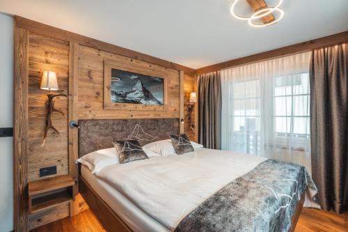 a bedroom with a large bed in a room with wooden walls at La Perle Apartments in Zermatt