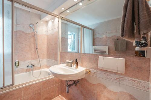 a bathroom with a sink and a shower and a mirror at La Perle Apartments in Zermatt