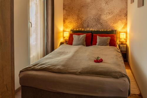 a bedroom with a large bed with red pillows at Sukorose Jacuzzis Vendégház in Sukoró