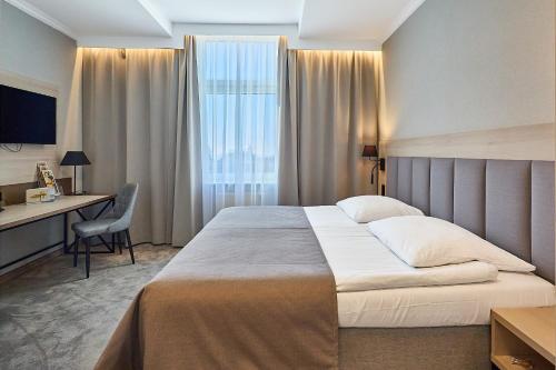 a hotel room with a bed and a desk and a window at Hotel Aurora Family & SPA in Międzyzdroje