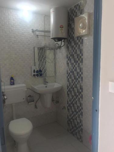 a bathroom with a white toilet and a sink at The Plum in Mukteshwar
