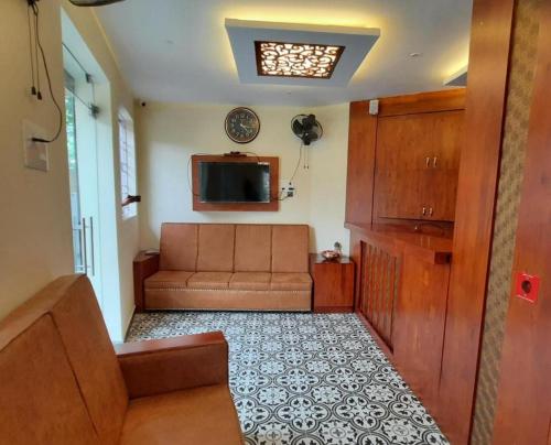 a living room with a couch and a television at ROYAL RESIDENCY Ac in Virudunagar