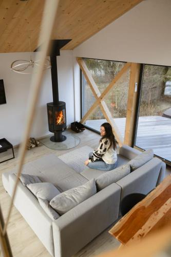 a woman sitting on a couch in a living room with a fireplace at Chalets Szőcs-birtok in Izvoare