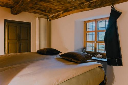 a bedroom with a bed with two pillows and a window at Corippo Albergo Diffuso in Corippo