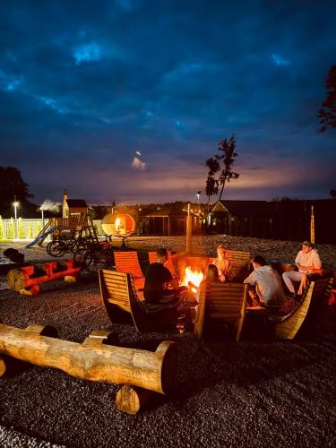 a group of people sitting around a camp fire at Raj nad jeziorem With Sauna Jacuzzi in Lubniewice