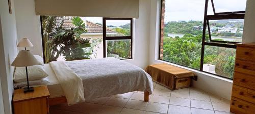 a bedroom with a bed and two large windows at Rivers Rest in Seafield