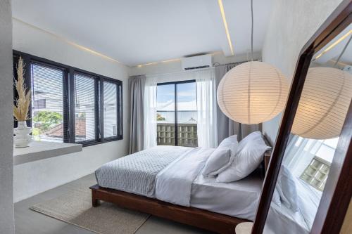 a bedroom with a bed and two large windows at Pyramid Ateliero Hotel Canggu in Canggu