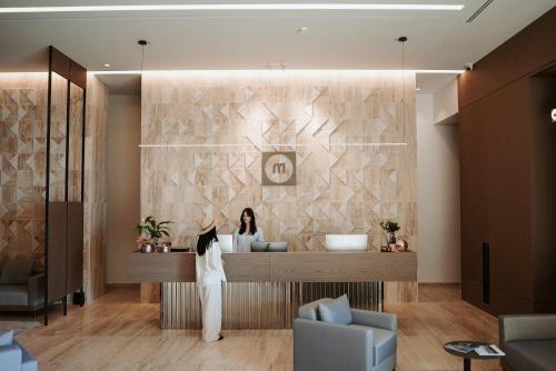 a woman standing at a reception desk in a lobby at Magnus Hotel & SPA in Vlorë