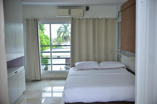 a bedroom with a bed and a large window at Elementz Apartments in Paramaribo