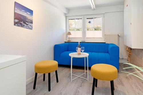 a living room with a blue couch and two stools at Alte Dorfstraße 29 REETungsinsel in Behrensdorf