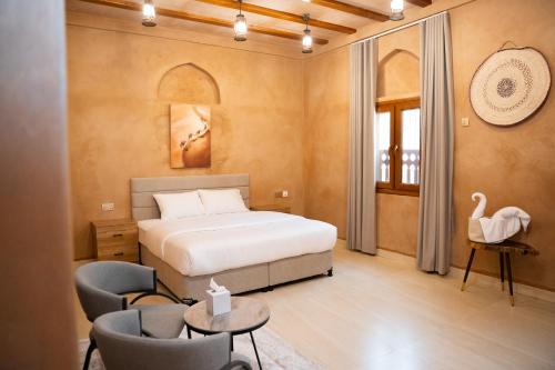 a bedroom with a bed and chairs and a swan on the wall at بيت المقصرة Almuqasrah house in Nizwa