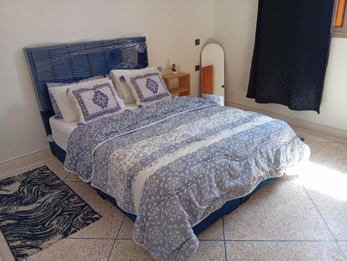 a bedroom with a bed with a blue comforter and pillows at Tafoukt House in Aourir