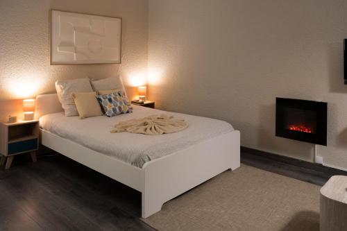 a bedroom with a white bed with a fireplace at L'Orée in Turckheim