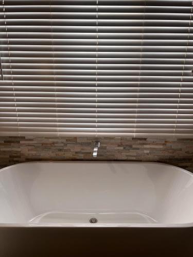 a white bath tub in front of a window at Jasmine Escape SPA Pool Secluded Bush Views in Ellalong