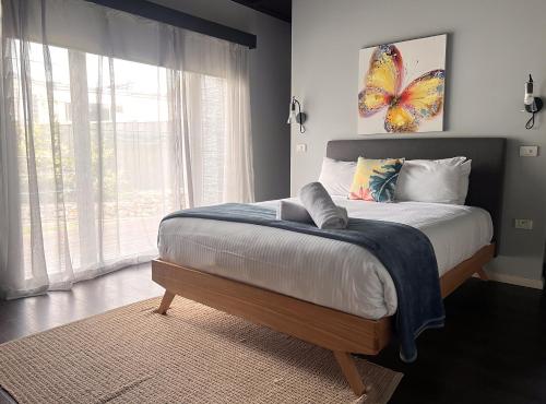 a bedroom with a bed with a butterfly painting on the wall at Jasmine Escape SPA Pool Secluded Bush Views in Ellalong