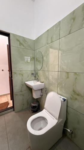 a bathroom with a white toilet and a sink at Uforia Munnar in Munnar