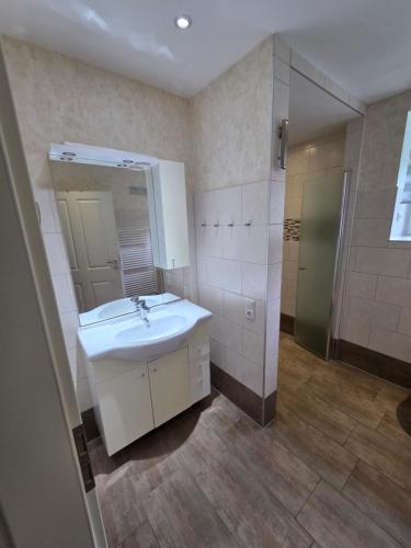 a bathroom with a sink and a mirror and a shower at Haus Küstenheide in Cuxhaven