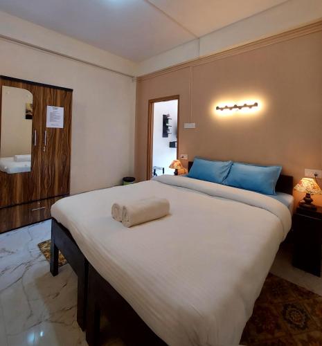 a bedroom with a large white bed with blue pillows at esS PHLYNDA Inn in Lāitlyngkot