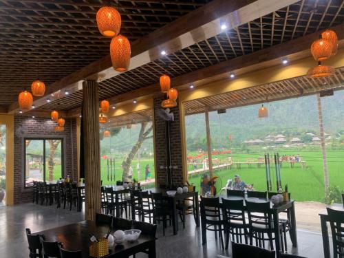 a restaurant with tables and chairs and a view of a field at Mai Chau Mountain Delight in Mai Châu